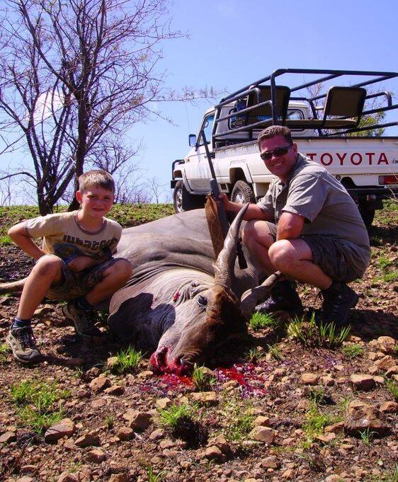 A hunter and his son posing with an eland